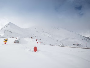 Ein schneebedeckter Berg mit Seilbahnen und einem kleinen Gebäude.