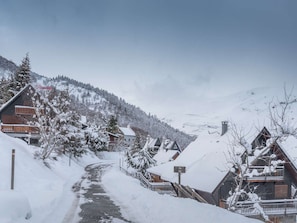 A snow-covered village with wooden houses, a winding path, and a mountain in the background. - 29m² Apartment for 6 near slopes in Saint-Lary-Soulan (Saint-Lary-Soulan)