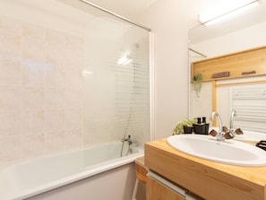 Ein modernes Badezimmer mit Duschkabine aus Glas, einem Holzlager für Waschbecken und einem Spiegel darüber.