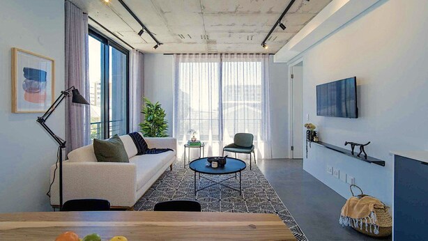 A modern living room with a sofa, coffee table, and a TV mounted on the wall. - Two Bed | Sea Point | Rooftop Pool (Cape Town)