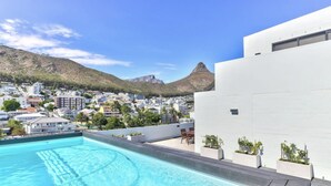 A rooftop pool with a clear view of a cityscape and mountains in the background. - Two Bed | Sea Point | Rooftop Pool (Cape Town)