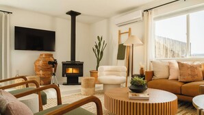 Un salon chaleureux avec une cheminée, des fauteuils confortables et un téléviseur à écran plat.