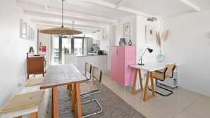 A modern kitchen with white cabinets, a wooden dining table, and a pink cabinet. - Two Bed | Table Mountain Views | Central (Cape Town)