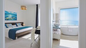 Ein modernes Schlafzimmer mit einem großen Bett, einem Schreibtisch und Meerblick.