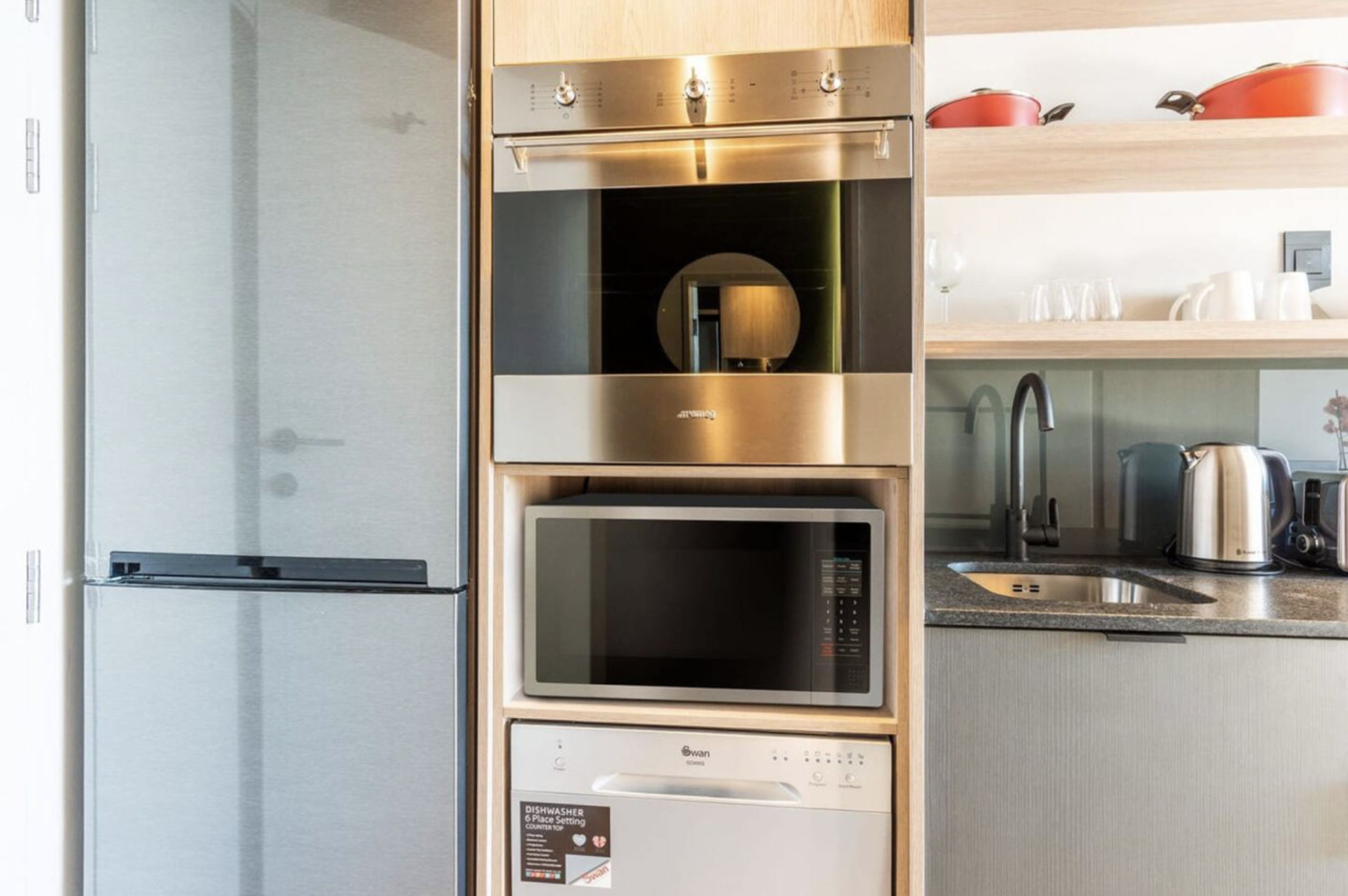 Una cucina con frigorifero in acciaio inossidabile, forno a microonde, forno e lavastoviglie.