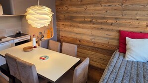 Ett modernt kök med en vit bänkskiva, en hängande lampa och en träpanel på väggen.