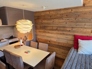 Une cuisine moderne avec un plan de travail blanc, un luminaire suspendu et un panneau mural en bois.