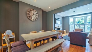 Ein modernes Wohnzimmer mit einem großen Holzesstisch, Bänken und einer Wanduhr.
