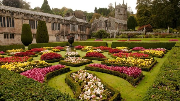 A formal garden with geometrically arranged flower beds and a historic building in the background. - 3 Bed in Torpoint (oc-l32511) (Downderry)
