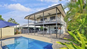 A two-story house with a balcony, a swimming pool, and a fenced yard.