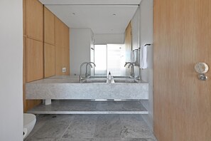 A modern bathroom with a large mirror, two sinks, and wooden cabinets. - Elegant One Bed | Sea Point | Mountain Views (Cape Town)