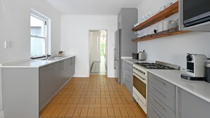 Una cocina moderna con armarios grises, suelo de baldosas, estufa, microondas y ventana.
