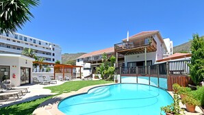 A swimming pool with a patio area, a covered seating area, and a building with multiple balconies. - Stylish Sea Point Studio in Secure Complex + Patio (Cape Town)