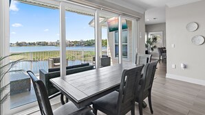 A spacious dining area with a view of the water, large windows, and a modern interior design. - 🏖️🎮🎲Lakefront | Private Pool | A Gamer's Getaway | Destin to Relax (Destin)