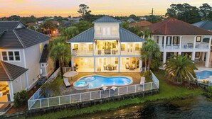 A large two-story house with a swimming pool, surrounded by a fence and palm trees. - 🏖️🎮🎲Lakefront | Private Pool | A Gamer's Getaway | Destin to Relax (Destin)
