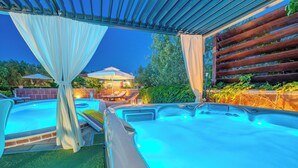 Un espace dédié aux bains à remous, comprenant deux bains à remous, une pergola et un coin salon agrémenté de parasols.