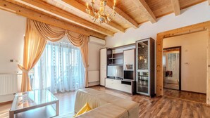 Un salon moderne avec une table basse en verre, un canapé avec des coussins, un plancher en bois, un téléviseur encastré et une cheminée en pierre.
