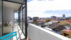 Un balcone con vista sulla città, un divano e una porta vetrata.