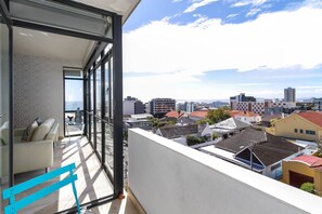 A balcony with a view of a cityscape, a sofa, and a glass door. - 2 Bed Bantry Bay | City and Sea View | 100m to Beach (Cape Town)