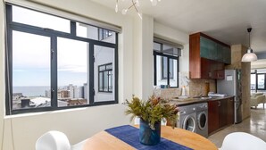 Una cucina moderna con vista sulla città, una zona pranzo con tavolo e sedie, e una lavatrice.