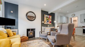 Een moderne woonkamer met een open haard, een flatscreen televisie, een bank en een eethoek.