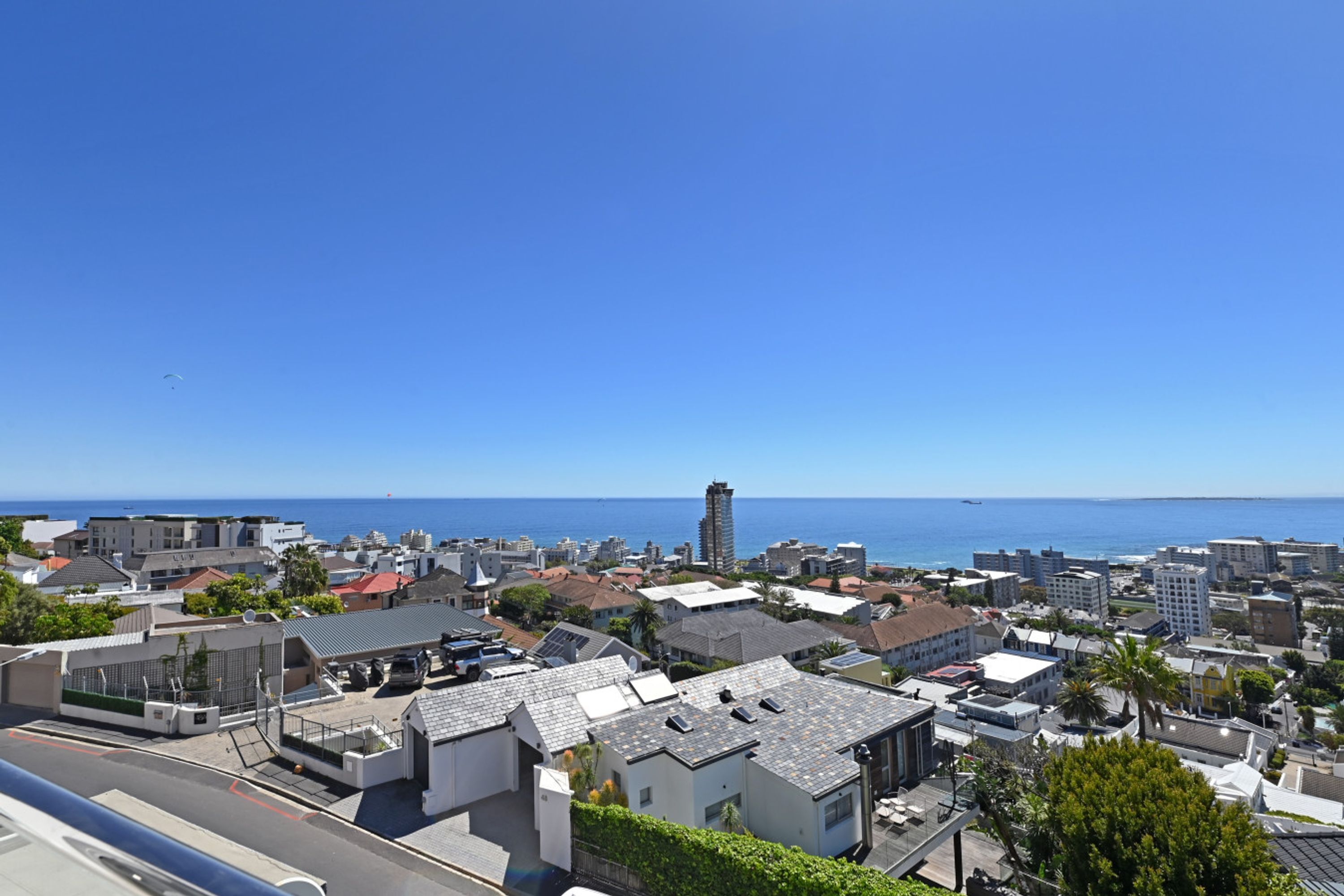 Uma cidade costeira com edifícios modernos, uma torre imponente e vista clara para o mar.