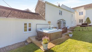 A backyard with a hot tub, a wooden deck, a barbecue grill, and a potted plant. - 3 Bed in Fairy Cross (oc-g32972) (Ford)