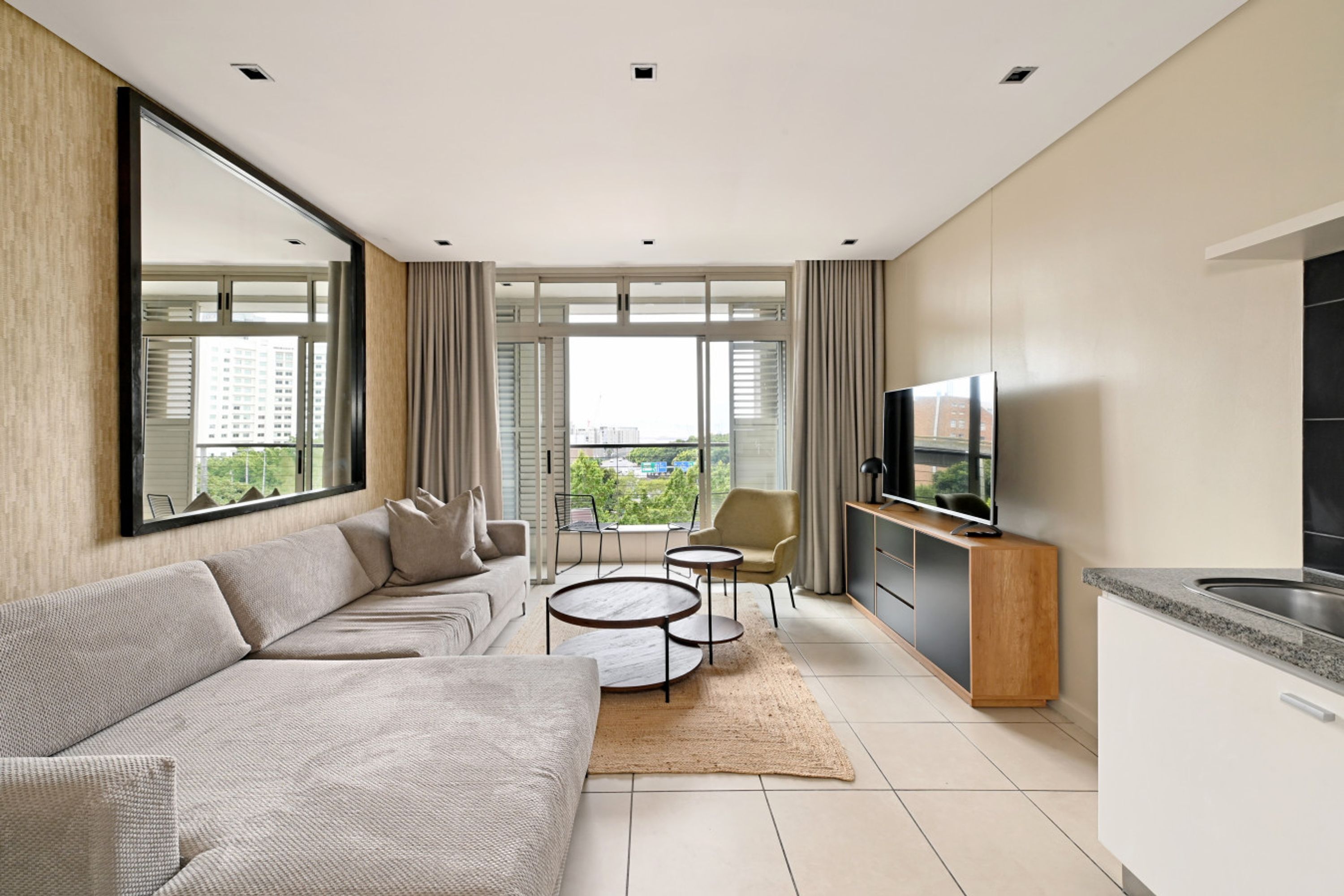 Ein modernes Wohnzimmer mit Sofa, Couchtisch, Fernseher und Essbereich.