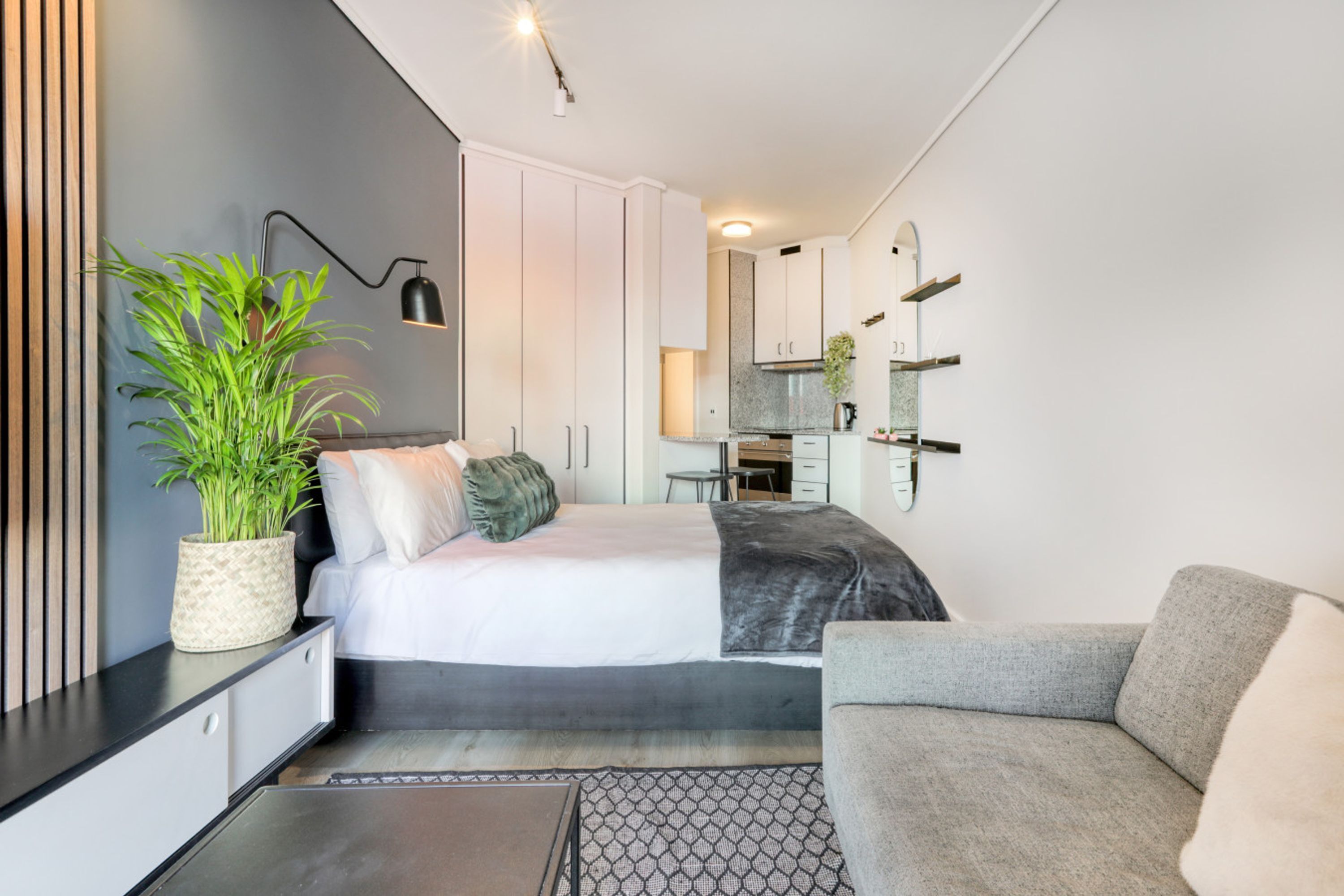 A modern bedroom with a bed, bedside table, and a potted plant.