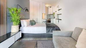 Un dormitorio moderno con cama, mesita de noche y una planta en maceta.