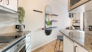 Una cocina moderna con encimeras de granito, campana de acero inoxidable y microondas.