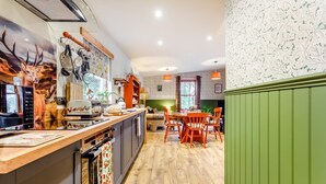 A modern kitchen with a wooden countertop, a dining area with orange chairs, and a green wall with a patterned wallpaper. - 2 Bed in Invergordon (oc-c33073) (Invergordon)