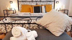 A neatly made bed with patterned bedding, a bedside table with a lamp, and a rolled towel on the floor. - B & B CELESTE BEDONIA 5 minutes from town center (Bedonia)