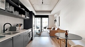 A modern kitchen with grey cabinets, a black countertop, and a dining area with a glass table and wooden chairs. - Station house | Studio Apartment | Gym |Rooftop Pool (Cape Town)