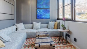 Una sala moderna con un sofá modular, una pequeña mesa redonda y una alfombra colorida.
