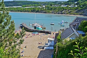 A coastal beach with a lifeguard station, boats, and a pier. - 2 Bed in Ponthirwaun (oc-h33292) (Ponthirwaun)