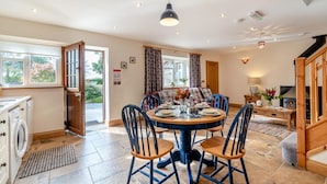 A well-lit dining area with a round table, chairs, and a view of the outdoors. - 2 Bed in Ponthirwaun (oc-c33293) (Ponthirwaun)