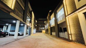 A nighttime view of a multi-story parking garage with cars parked on the ground floor.