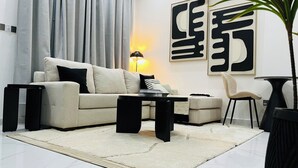 Een moderne woonkamer met een bank, salontafel, bijzettafeltje, lamp en stoel.