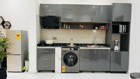 Una cocina compacta con lavadora y secadora integradas, un microondas y un lavabo.
