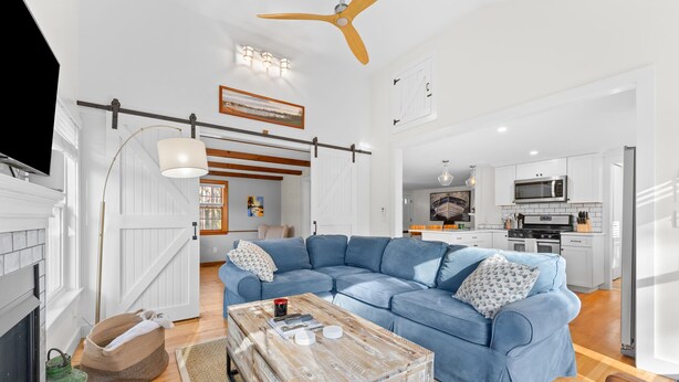 A modern living room with a blue sectional sofa, a wooden coffee table, and a kitchen in the background. - Coastal comfort near beaches and walking distance to Harwich Port! (Harwich)