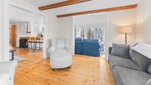 A spacious living room with a wooden floor, a white armchair, a grey sofa, and a blue couch. - Coastal comfort near beaches and walking distance to Harwich Port! (Harwich)