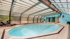 An indoor swimming pool with a glass ceiling, lounge chairs, and a blue wall. - 3 Bed in Fowey (oc-o33078) (Fowey)