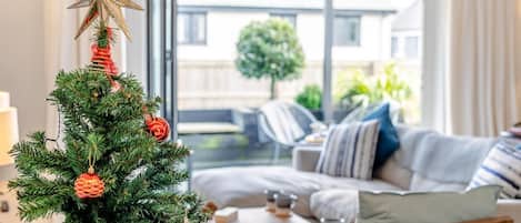 A modern living room with a Christmas tree, a star ornament, and a sofa with cushions.