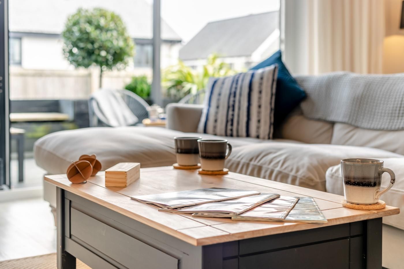 A modern bedroom with a wooden desk, a bed with a striped pillow, and a view of the outdoors.