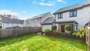 A residential area with a well-maintained lawn, a wooden fence, and houses with pitched roofs. - 3 Bed in Fowey (oc-s33234) (Fowey)
