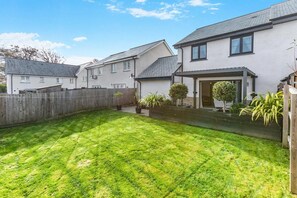 A residential area with a well-maintained lawn, a wooden fence, and houses with pitched roofs. - 3 Bed in Fowey (oc-s33234) (Fowey)