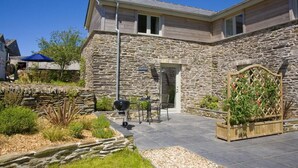 A stone house with a patio, outdoor seating, and a garden. - 1 Bed in Bodmin (oc-p00377) (Trevisquite Manor)