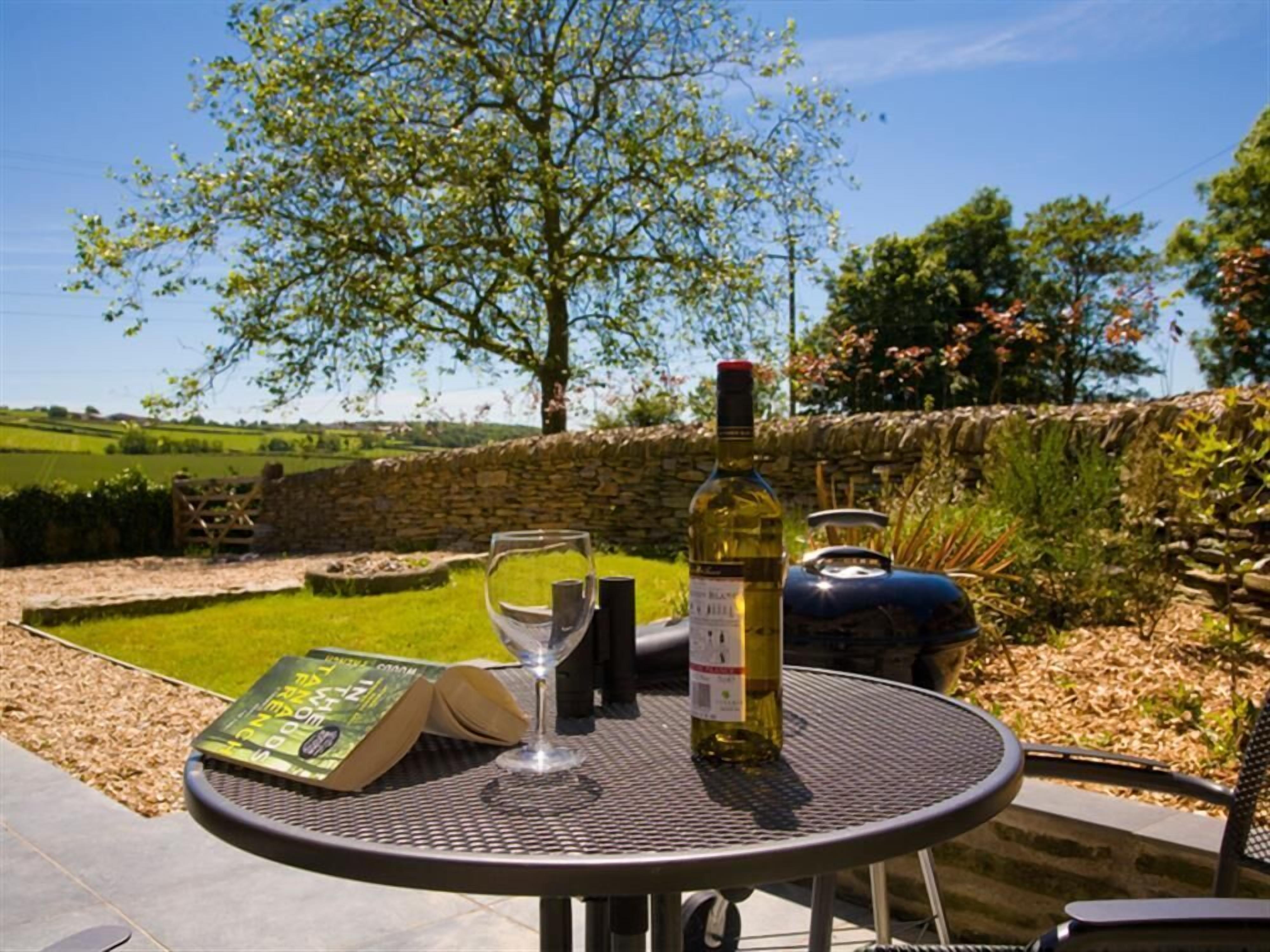 An outdoor patio with a round metal table, a wine bottle, and a wine glass.