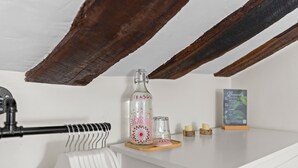 A white shelf with a glass bottle, a glass, and a small candle. - Casa Rural Selmo in the Heart of Asturias (Zancornio)